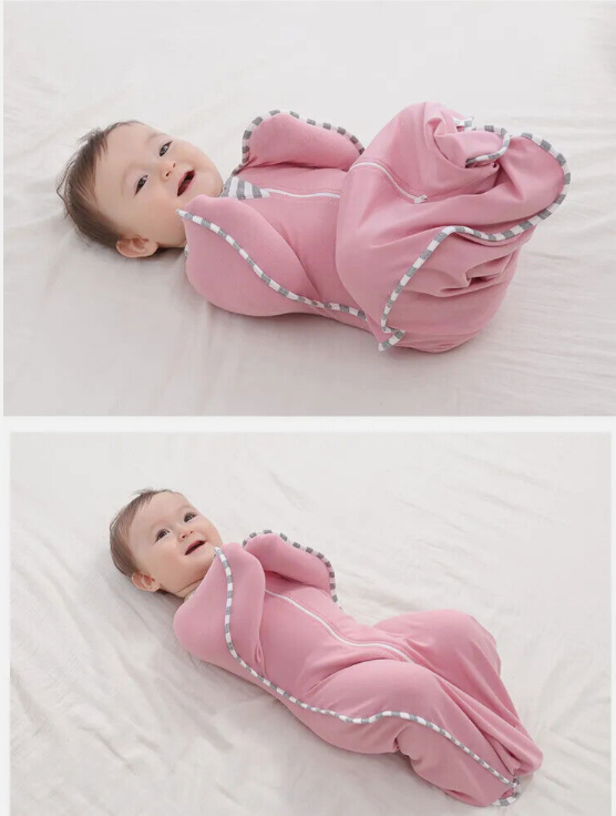 Baby in a pink sleeping bag on a white blanket