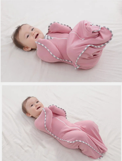 Baby in a pink sleeping bag on a white blanket